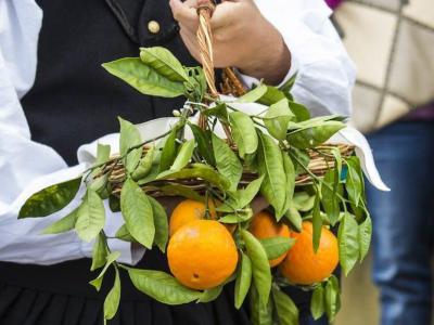 Persona con abito tradizionale e cesto di arance.