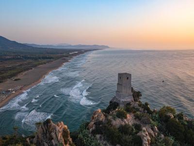 Vista costiera al tramonto con torre su scogliera.