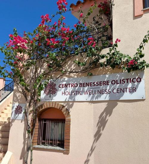 Centro benessere olistico con fiori colorati e cielo azzurro.