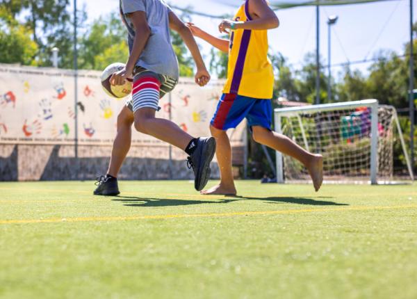 Ragazzi giocano a calcio su un campo all'aperto.