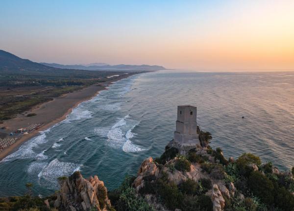 Vista costiera al tramonto con torre su scogliera.