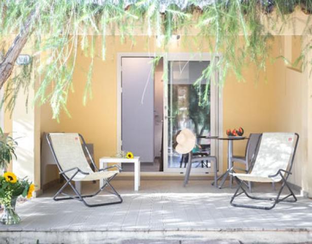 Terrasse mit Stühlen, Tisch und Pflanzen, entspannte Atmosphäre.